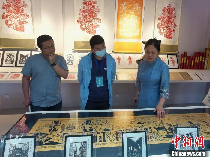 安徽省非遗徽州剪纸传承人吴笑梅(右一)在介绍自己的作品。　张强 摄